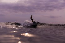 Männliches Surfen zwischen wogendem Meer mit Spritzern und bewölktem Himmel am Abend auf Bali, Indonesien — Stockfoto