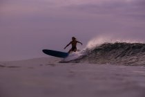 Männliches Surfen zwischen wogendem Meer mit Spritzern und bewölktem Himmel am Abend auf Bali, Indonesien — Stockfoto