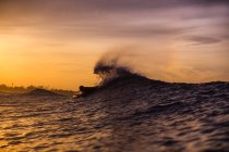 Vue latérale du mâle flottant sur la planche de surf entre l'eau de mer et le ciel nuageux sur Bali, Indonésie — Photo de stock