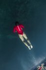 Von oben taucht eine Frau im roten Badeanzug im blauen Meer auf Bali, Indonesien — Stockfoto