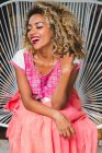 Portrait of happy black young woman with closed eyes and curly hair sitting on wicker chair — Stock Photo