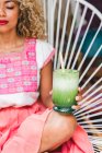 Close-up of relaxed black young woman holding shake in glass and sitting on wicker chair — Stock Photo