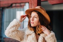 Позитивна приваблива молода жінка в теплому одязі і капелюсі дивиться геть — стокове фото