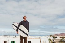 Sorrindo homem de pé com prancha de surf — Fotografia de Stock
