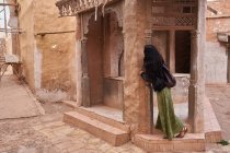 Бічний вид на молоду жінку, що стоїть біля будинку ретро на вулиці в Марракеші, Марокко. — стокове фото