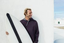 Улыбающийся мужчина стоит с доской для серфинга — стоковое фото