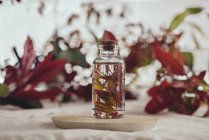 Bottle with fresh plant in liquid on board on blurred background — Stock Photo