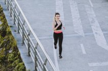 Сверху женщины в спортивной одежде бегают по набережной возле воды в городе — стоковое фото