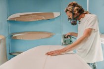 Homem com ferramenta de serrar prancha de surf na oficina — Fotografia de Stock