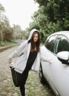 Женщина в спортивной одежде, растянувшаяся возле машины в парке — стоковое фото