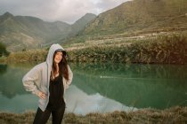 Positive Frau macht Pause nach dem Laufen in der Natur in der Nähe von See und Bergen — Stockfoto