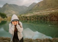 Femme positive faisant une pause après avoir couru dans la nature près du lac et des montagnes — Photo de stock