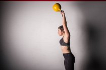 Athlète jeune femme concentrée dans les vêtements de sport kettlebell upping dans la salle de gym — Photo de stock