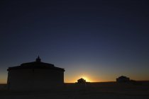 Exterior de antigua casa de piedra en paisaje rural bajo majestuoso cielo en estrellas por la noche - foto de stock