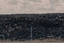 Enorme pilha de pneus antigos auto entre o prado — Fotografia de Stock