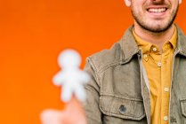 Happy guy showing paper silhouette for April fools day on orange blurred background - foto de stock
