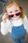 Jeune fille mignonne essayant des lunettes dans un magasin de lunettes — Photo de stock