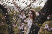 Гілочки квітучого фруктового дерева і молода жінка, дивлячись в природу — стокове фото