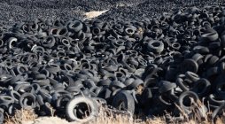 Enorme mucchio di vecchi pneumatici auto tra prato — Foto stock