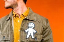 Crop ragazzo felice con silhouette di carta per aprile sciocchi giorno sulla giacca di jeans su sfondo arancione — Foto stock