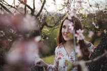 Zweige blühender Obstbäume und junge Frau, die in der Natur wegschaut — Stockfoto