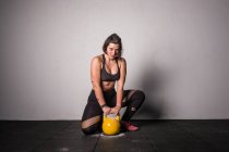 Атлетичная молодая сконцентрированная женщина в спортивной одежде, поднимающая гири в спортзале — стоковое фото