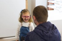 Menina bonito tentando em óculos em uma loja de óculos — Fotografia de Stock