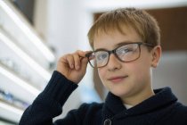 Милый мальчик примеряет очки в магазине очков. — стоковое фото