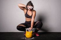 Atletica giovane donna concentrata in abbigliamento sportivo alzando il kettlebell in palestra — Foto stock