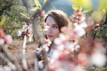 Гілочка квітучого фруктового дерева і вдумлива молода жінка, дивлячись в природу — стокове фото