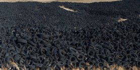 Enorme pilha de pneus antigos auto entre o prado — Fotografia de Stock