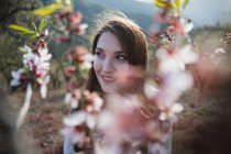 Twig of blooming fruit tree and smiling young woman looking away in nature — Stock Photo