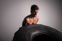 Atlético jovem shirtless cara ter competição de lançando grandes pneus no ginásio — Fotografia de Stock