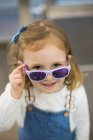 Linda chica joven probándose gafas en una tienda de gafas - foto de stock