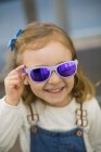 Cute young girl trying on glasses in an eyewear store — Stock Photo