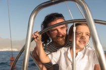 Buon padre con bambini che galleggiano su costose barche in mare e cielo blu nella giornata di sole — Foto stock