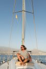 Homem adulto barbudo positivo em óculos de sol sentado flutuando em barco caro no mar em dia ensolarado — Fotografia de Stock