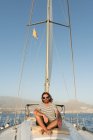 Позитивний бородатий дорослий чоловік в сонцезахисних окулярах, що плаває на дорогому човні на морі в сонячний день — стокове фото
