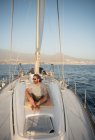 Positiv bärtiger erwachsener Mann mit Sonnenbrille, der an sonnigen Tagen auf einem teuren Boot auf dem Meer schwimmt — Stockfoto