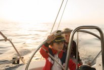 Позитивні діти в капелюсі капітана плавають на дорогому човні на морі в сонячний день — стокове фото