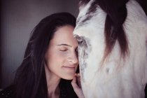 Attraente donna affascinante con gli occhi chiusi toccare cavallo in stalla — Foto stock