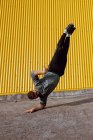 Junger Mann macht Handstand, während er in der Nähe der Mauer eines modernen Gebäudes an der Stadtstraße tanzt — Stockfoto