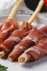 Gressinis with spanish typical serrano ham on white platter — Stock Photo