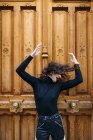 Femme posant dans une grande porte en bois marron — Photo de stock