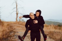 Счастливая гомосексуальная пара веселится на пути между растениями в горах — стоковое фото