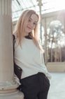 Стильна посміхаючись молода жінка, спираючись на пост в Кришталевий палац в Мадриді, Іспанія — стокове фото
