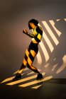 Attraente sottile femminile che esegue movimento di danza sotto la luce intensa dalla finestra — Foto stock