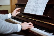 Вид сбоку человека, играющего на фортепиано в музыкальной студии — стоковое фото