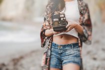 Closeup of woman holding camera on shore on blurred background — Stock Photo