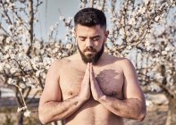 Homem sem camisa meditando no jardim da primavera — Fotografia de Stock